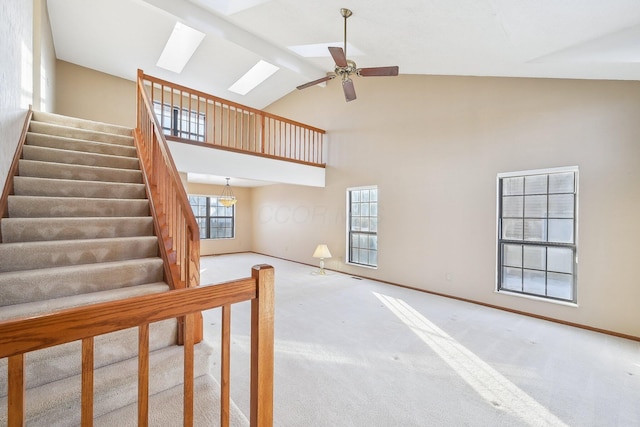 interior space with a skylight, high vaulted ceiling, carpet flooring, and ceiling fan