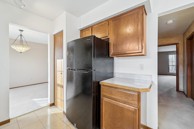 kitchen featuring black refrigerator, light colored carpet, and pendant lighting