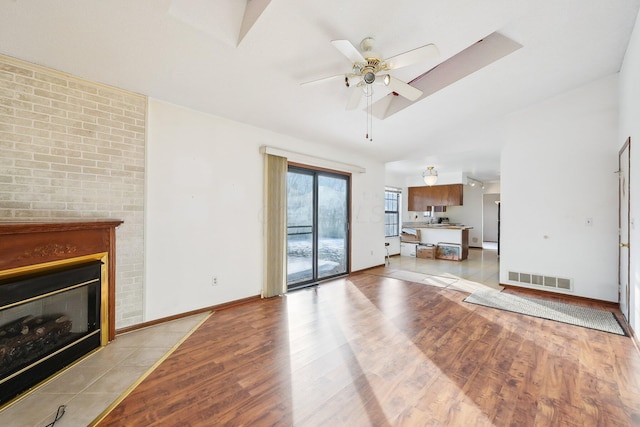 living room with a fireplace, light hardwood / wood-style floors, and ceiling fan