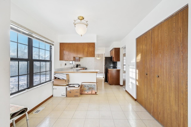 kitchen featuring kitchen peninsula, a healthy amount of sunlight, and black fridge