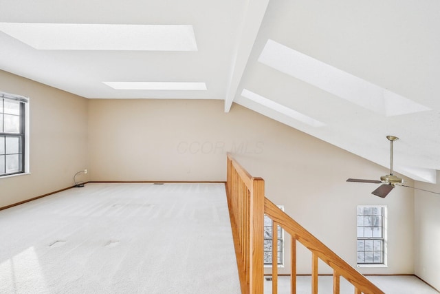 additional living space with carpet flooring, ceiling fan, and lofted ceiling with skylight