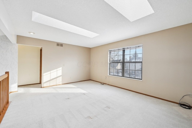 unfurnished room featuring light colored carpet, a textured ceiling, and a skylight