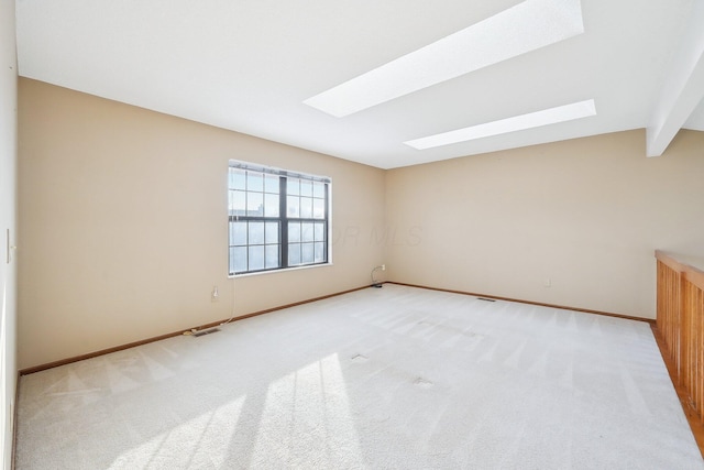 unfurnished room featuring lofted ceiling with skylight and light carpet