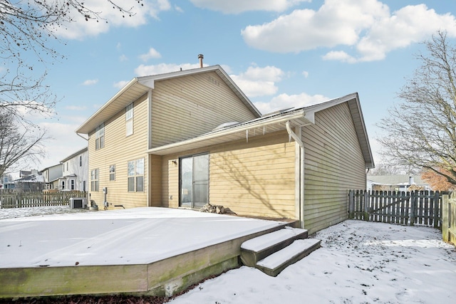 snow covered rear of property featuring central AC unit