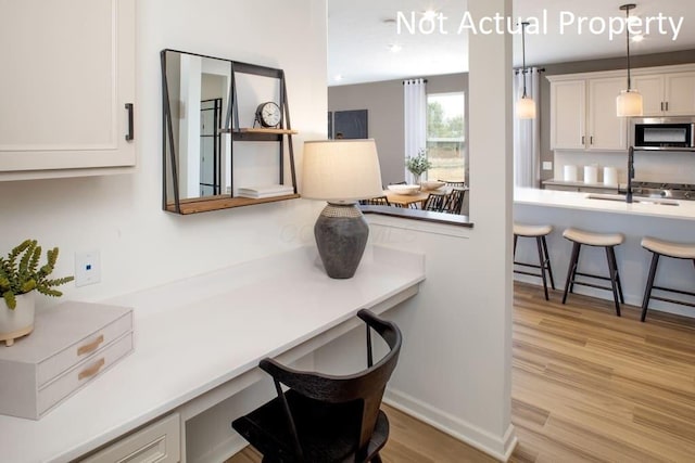 interior space with sink, built in desk, and light hardwood / wood-style flooring