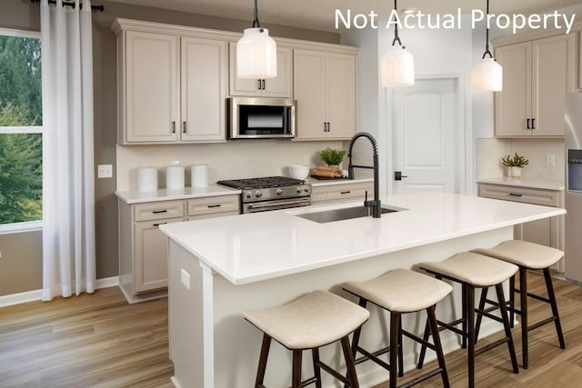 kitchen with sink, a breakfast bar area, stainless steel appliances, and an island with sink