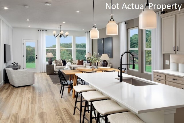 kitchen with a spacious island, sink, a breakfast bar area, hanging light fixtures, and light hardwood / wood-style floors