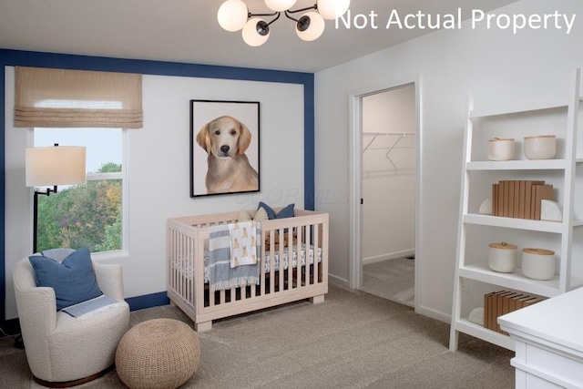 carpeted bedroom with an inviting chandelier, a closet, a walk in closet, and a nursery area