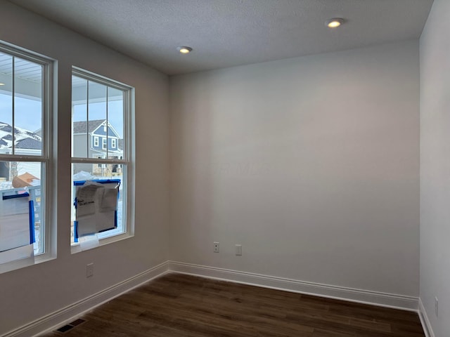 unfurnished room with dark wood-type flooring and a textured ceiling