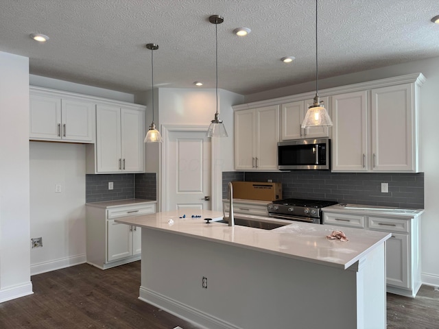 kitchen featuring stainless steel appliances, white cabinetry, and a kitchen island with sink