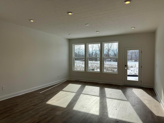 unfurnished room featuring dark wood-type flooring and a textured ceiling