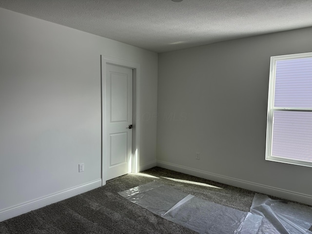 carpeted empty room with a textured ceiling