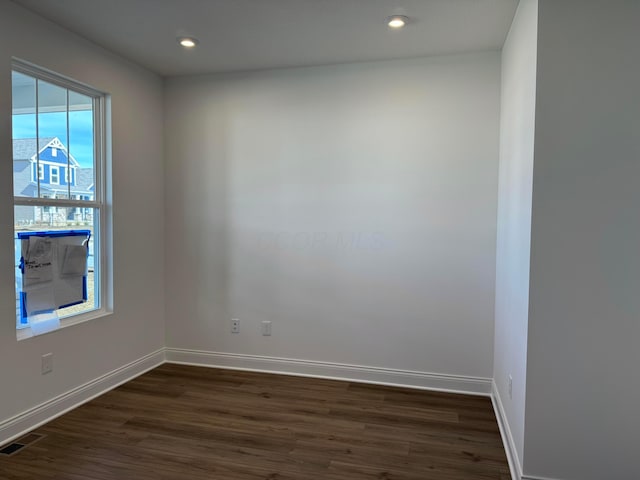 empty room featuring visible vents, baseboards, dark wood-type flooring, and recessed lighting