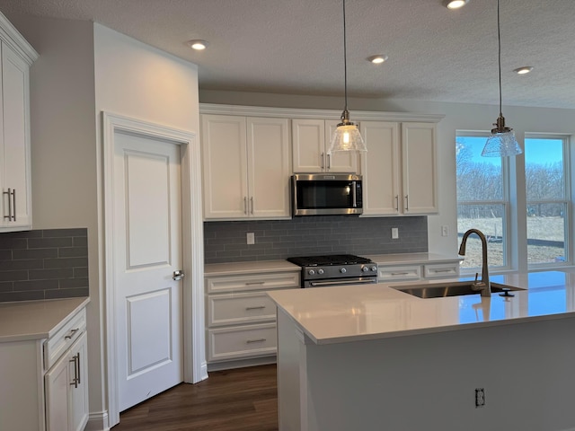 kitchen featuring dark wood-style flooring, light countertops, appliances with stainless steel finishes, white cabinets, and a sink