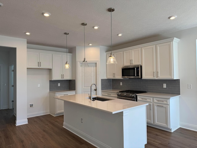 kitchen with appliances with stainless steel finishes, a sink, a center island with sink, and white cabinets