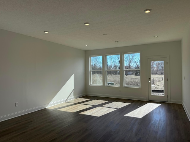 empty room with baseboards, dark wood finished floors, a textured ceiling, and recessed lighting