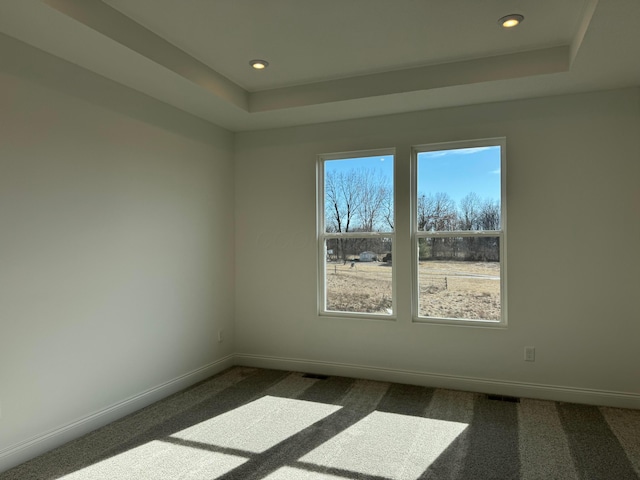 empty room featuring recessed lighting, a raised ceiling, dark carpet, and baseboards