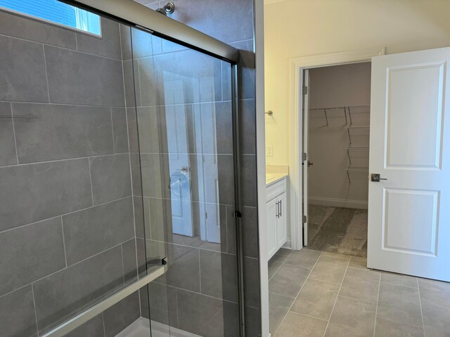 full bath featuring tile patterned flooring, a shower stall, vanity, and a spacious closet