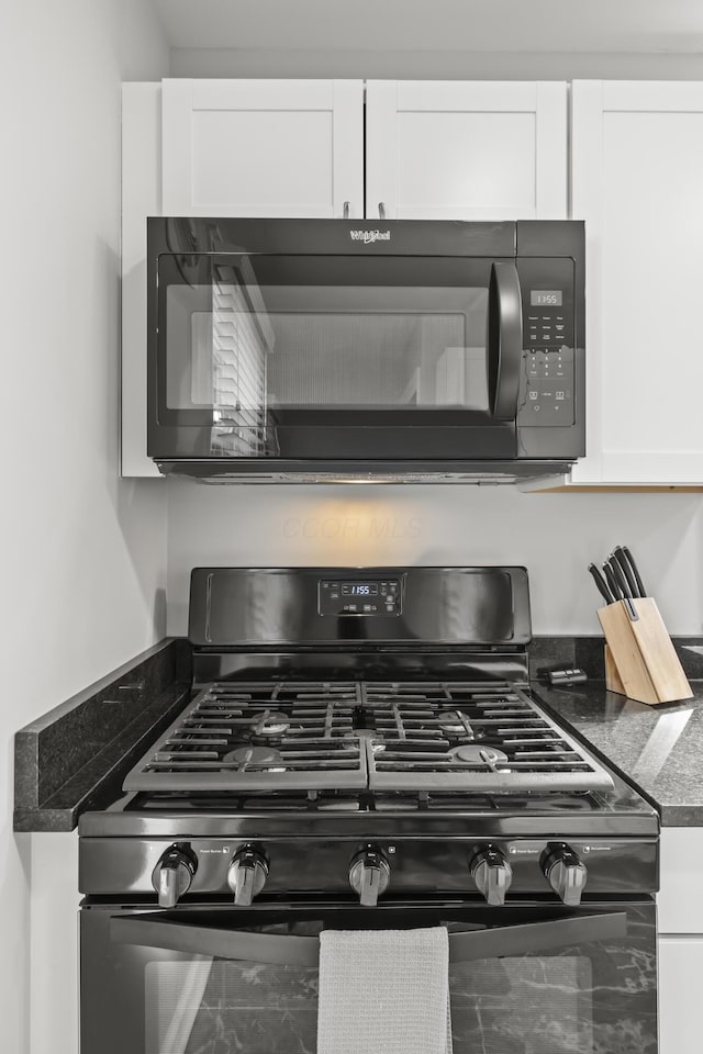 interior details featuring black gas range and white cabinets