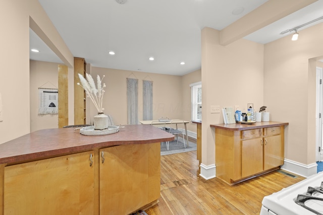 kitchen with rail lighting, light hardwood / wood-style floors, kitchen peninsula, and beamed ceiling