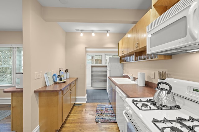 kitchen featuring sink, white appliances, track lighting, and light hardwood / wood-style floors