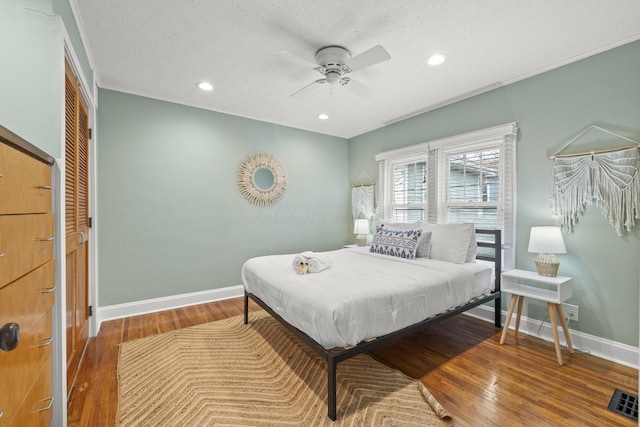 bedroom with hardwood / wood-style floors, a textured ceiling, a closet, and ceiling fan