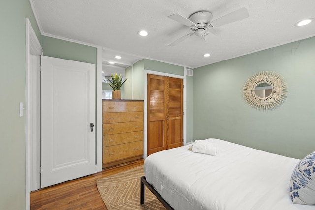 bedroom featuring hardwood / wood-style flooring, ceiling fan, a closet, and a textured ceiling