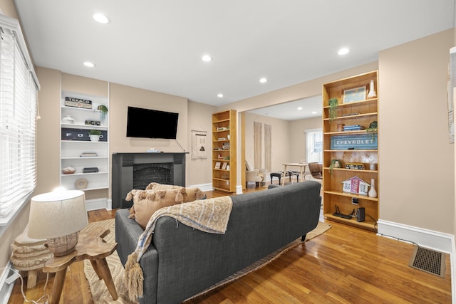 living room featuring built in features and light hardwood / wood-style floors