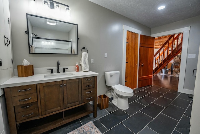 bathroom featuring a textured ceiling, toilet, and vanity