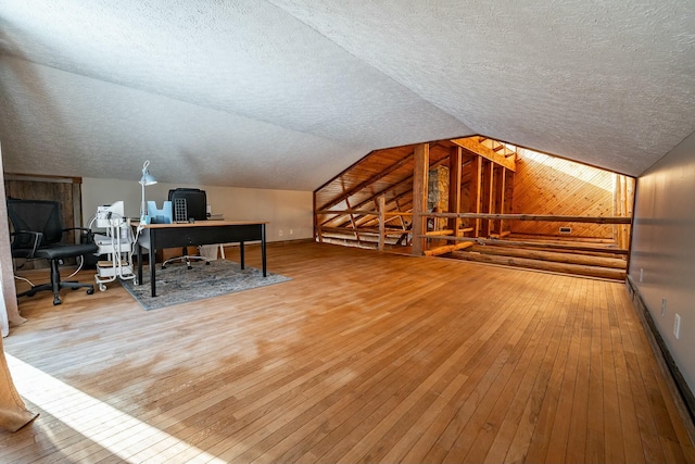 bonus room with baseboard heating, hardwood / wood-style floors, wood walls, and vaulted ceiling