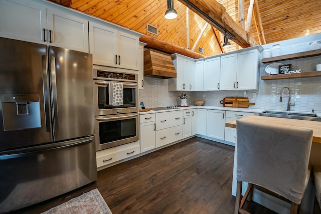 kitchen with wooden ceiling, premium range hood, white cabinets, sink, and stainless steel appliances