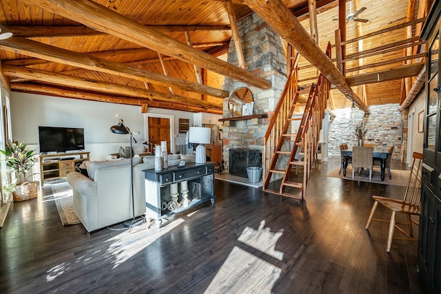 living room featuring wood ceiling, dark wood-type flooring, a stone fireplace, beamed ceiling, and high vaulted ceiling