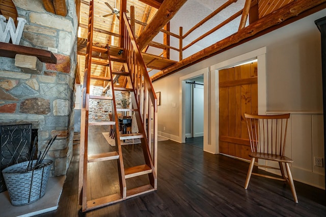 stairs featuring hardwood / wood-style floors, a fireplace, a barn door, high vaulted ceiling, and ceiling fan