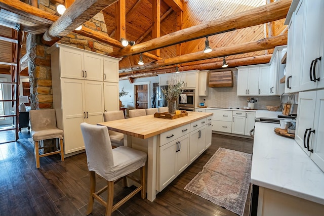 kitchen featuring white cabinets, tasteful backsplash, a kitchen island, and wood counters