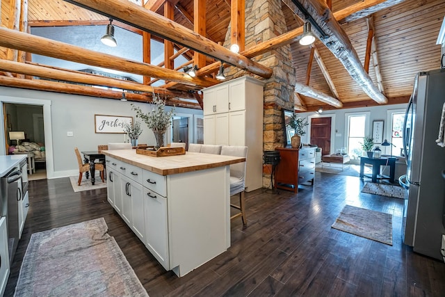 kitchen with white cabinetry, stainless steel fridge, a center island, and beamed ceiling