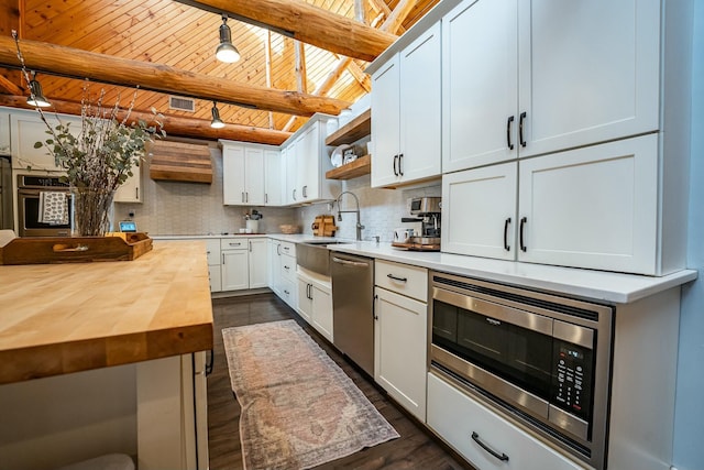 kitchen with appliances with stainless steel finishes, white cabinets, tasteful backsplash, wooden ceiling, and beamed ceiling