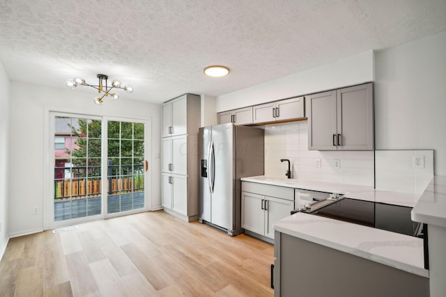 kitchen with tasteful backsplash, stainless steel fridge with ice dispenser, gray cabinets, and a textured ceiling