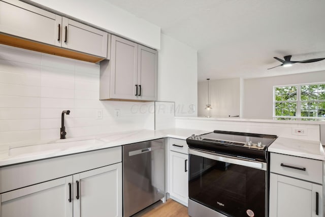 kitchen featuring appliances with stainless steel finishes, decorative light fixtures, sink, gray cabinetry, and decorative backsplash