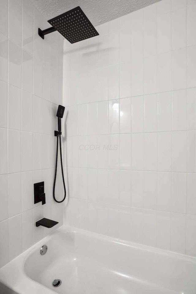 bathroom with tiled shower / bath and a textured ceiling