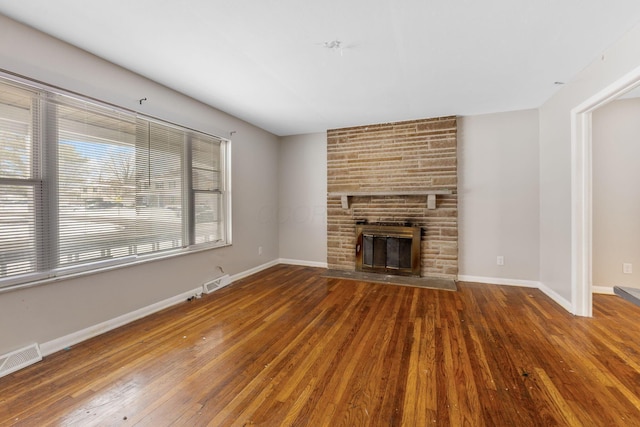 unfurnished living room featuring wood-type flooring and a large fireplace