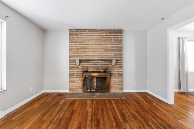 unfurnished living room featuring dark wood-type flooring and a fireplace