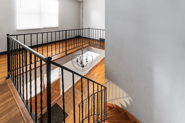 stairway with a notable chandelier and wood-type flooring