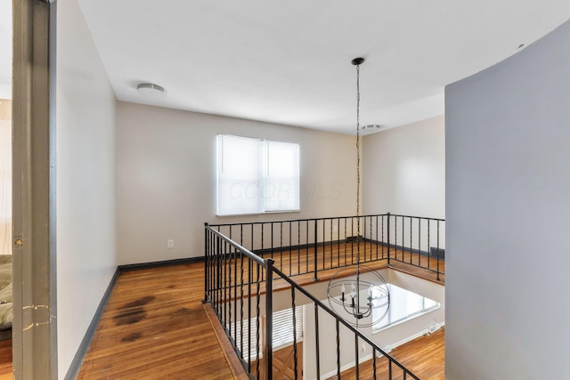 corridor featuring an inviting chandelier and hardwood / wood-style flooring