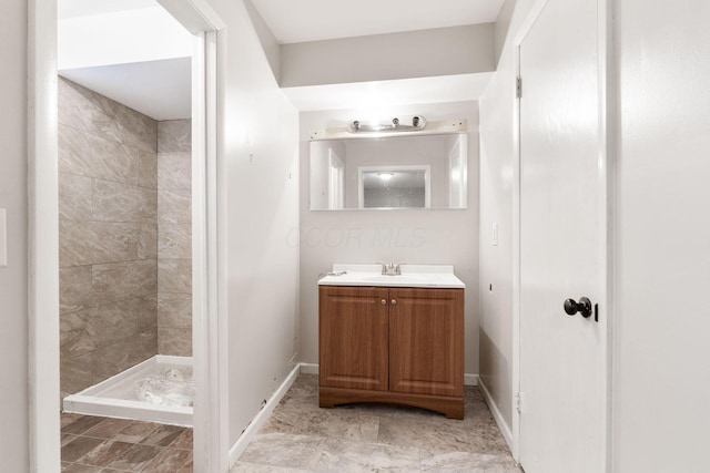 bathroom with tiled shower and vanity