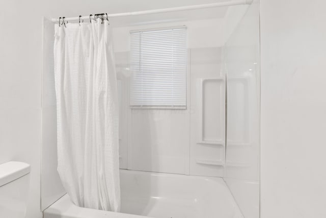 bathroom with shower / bathtub combination with curtain and toilet