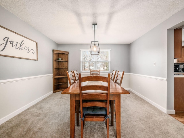 dining area with light colored carpet and a textured ceiling