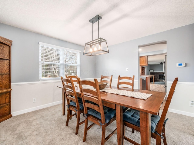 dining area with light colored carpet and a textured ceiling