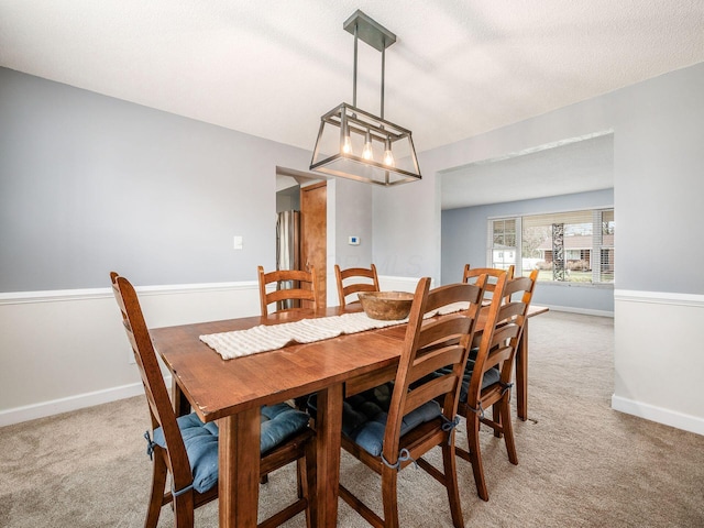 carpeted dining space featuring a textured ceiling