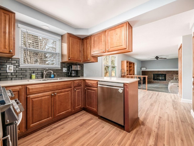 kitchen featuring sink, dishwasher, a wealth of natural light, a fireplace, and kitchen peninsula