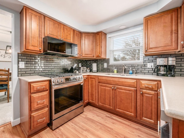 kitchen featuring tasteful backsplash, stainless steel range with gas cooktop, sink, and light wood-type flooring